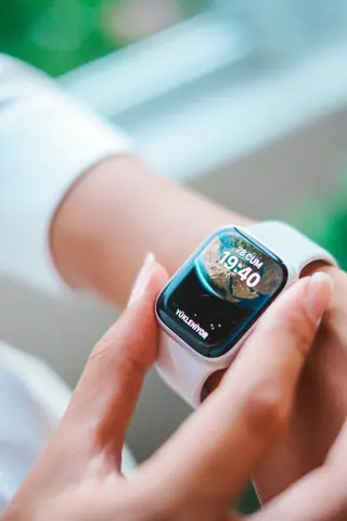 Close-up of a person's hand adjusting a smartwatch indoors. Technology focus.