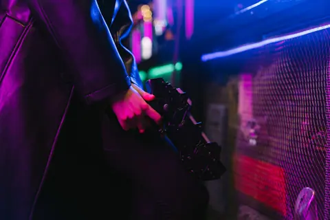 Person holding a futuristic gun with vibrant neon cyberpunk aesthetics.