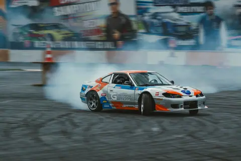 High-performance car drifting with smoke at a dynamic motorsport event. Action and speed captured vividly.