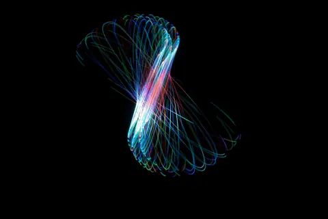 Vibrant, colorful light trails creating abstract patterns on a black surface.