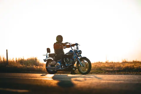 Solo ride at sunset on a highway featuring a motorcyclist in a serene landscape.