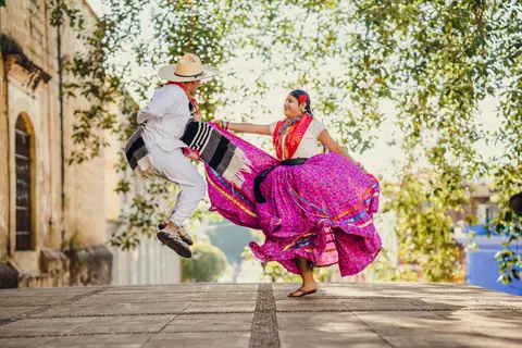 A colorful tradition unfolds with dancers in vibrant attire celebrating in the streets of Oaxaca, Mexico.