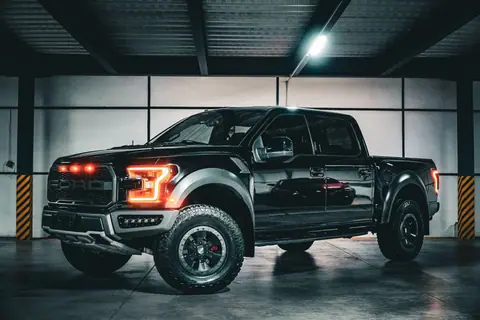 Bold black pickup truck with illuminated lights in an industrial garage.