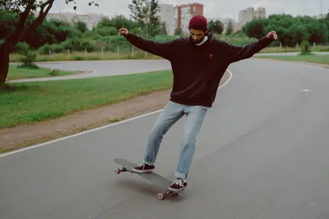 A young man skateboarding on a curved path in a park, showcasing skill and leisure.