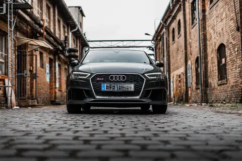 Front view of a car parked between rustic brick buildings in a city.