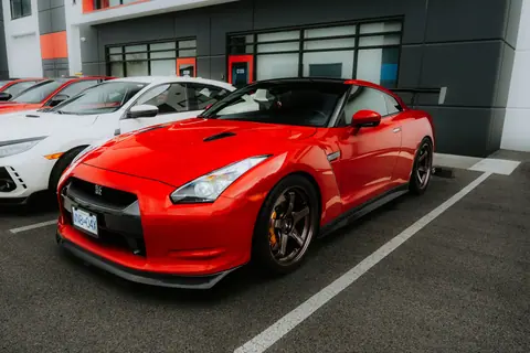 Sleek red sports car parked in an urban area, showcasing modern design and dynamic appeal.
