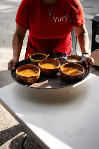 Candid shot of a server presenting bowls of soup outdoors, vibrant sunlight scene.
