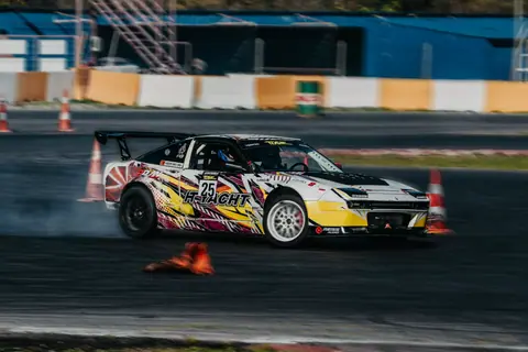 A dynamic shot of a race car drifting on a track, showcasing speed and precision.