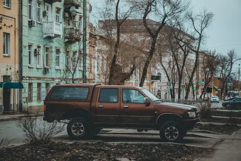 A vintage pickup truck parked on a quiet urban street lined with historic buildings.