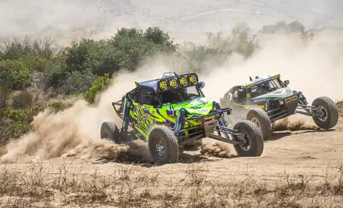 Dynamic off-road rally cars racing through dusty desert terrain in Tijuana, Mexico.