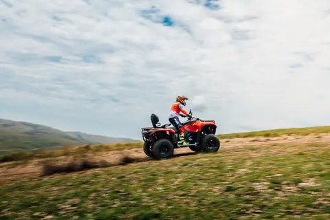 A thrilling off-road ride on a quad bike in a scenic landscape under a partly cloudy sky.