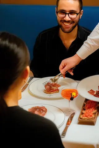 Couple enjoying a romantic dinner with gourmet dishes and drinks in a cozy restaurant.