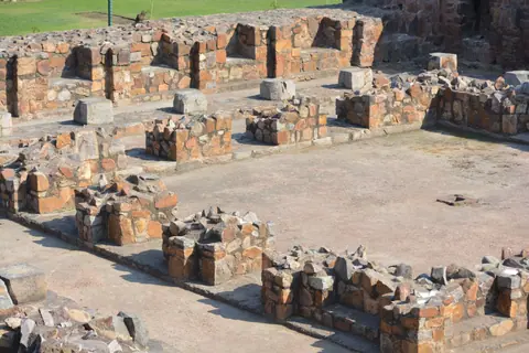 Stone ruins of ancient Firoz Shah Kotla fort in Delhi on a bright day.