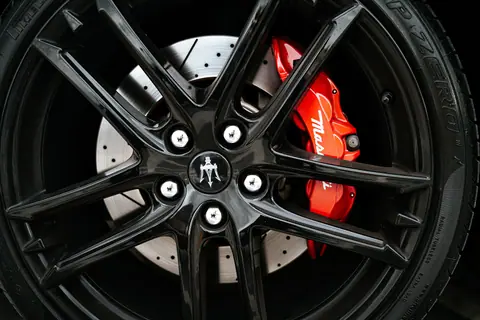 Stunning close-up of Maserati car wheel featuring shiny alloy rim and red brake caliper.