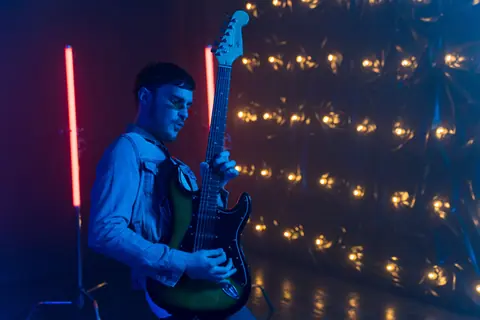 Musician passionately playing electric guitar under vibrant stage lights.