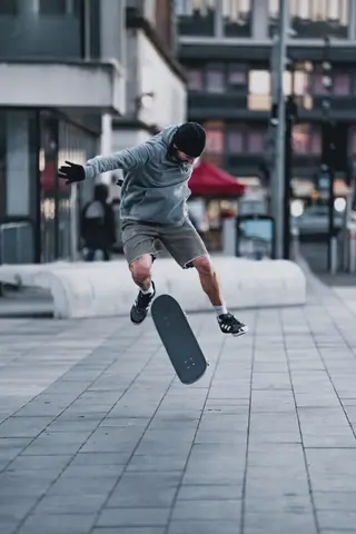 Skateboarder executes a mid-air trick on a city sidewalk, showcasing skill and urban lifestyle.