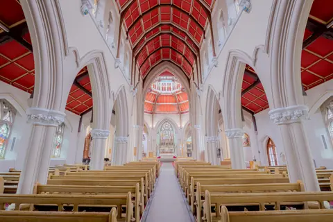 Stunning view of a gothic church interior showcasing intricate arches and red ceilings.