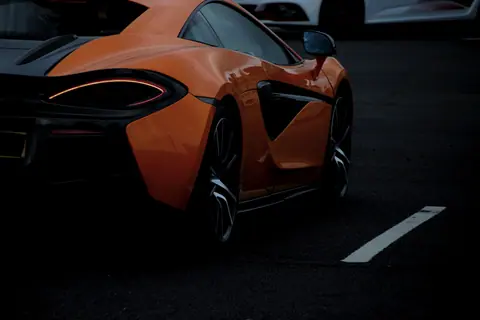 Luxurious orange sports car parked in England, showcasing elegant curves and design.