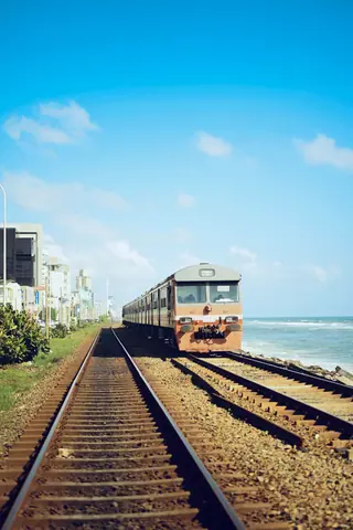 A train travels along a scenic track by the ocean, highlighting the beauty of coastal travel.