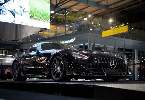 Sleek black luxury sports car showcased at a Munich automotive exhibition, highlighting elegance.