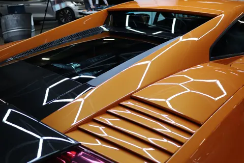Detailed image of a yellow sports car engine area with reflective surfaces and sleek design.