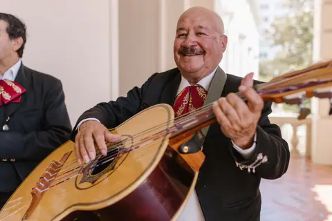 Smiling mariachi musician performing with a guitarrón, showcasing Mexican culture.