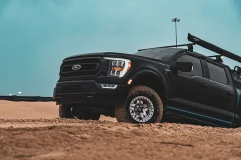 A black Ford F-150 pick-up conquers the sandy desert under a clear sky.