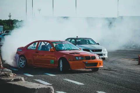 Dynamic scene of car drifting on track creating smoke clouds during an adrenaline-fueled competition.