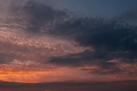 Explore a stunning sunset with dramatic clouds and vivid hues, captured in a summer evening sky.