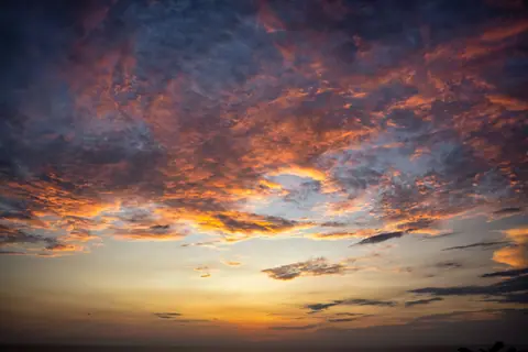 Vibrant sunset captured over Bali, Indonesia, showcasing dramatic cloud formations and vivid colors.
