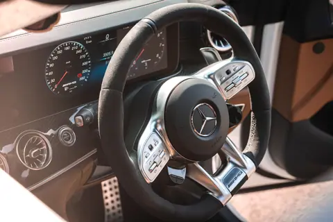 Detailed view of a Mercedes steering wheel and dashboard with emblem and gauges.