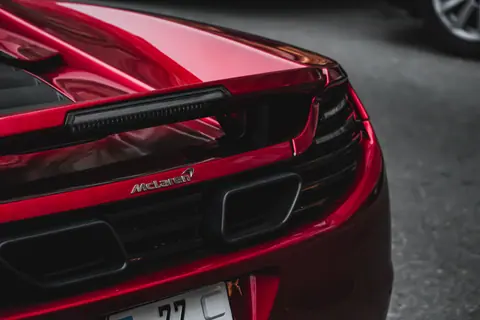 Elegant rear view of a red McLaren MP4-12C supercar showcasing its sleek design and powerful presence.