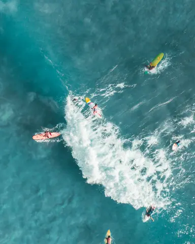 Dynamic aerial shot capturing surfers riding ocean waves, showcasing vibrant water sports action.