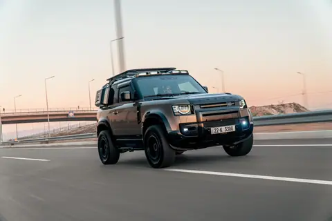 Dynamic shot of a Land Rover Defender speeding on a highway in Erbil, Iraq at sunset.