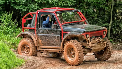 Muddy Suzuki 4x4 vehicle navigating an off-road trail in Stadtoldendorf, Germany.