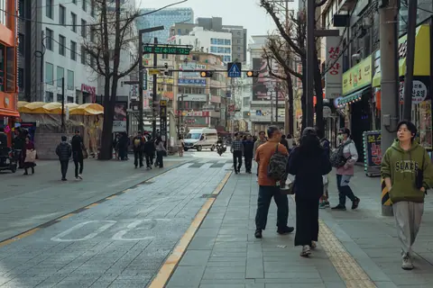Discover the bustling streets of Seoul with people enjoying city life on a sunny day.