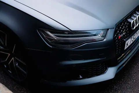 A detailed view of a sleek black luxury car's front headlight and grill.