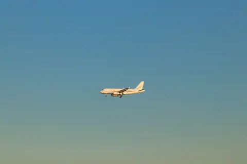 A commercial airplane flying against a clear blue sky during the day in Istanbul.