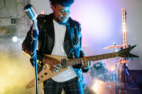 A musician passionately playing electric guitar at a vibrant concert with colorful stage lights.