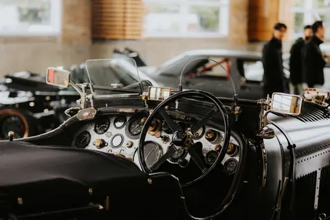 Intricate interior of a vintage car showcasing a classic dashboard and steering wheel at an automotive exhibition.
