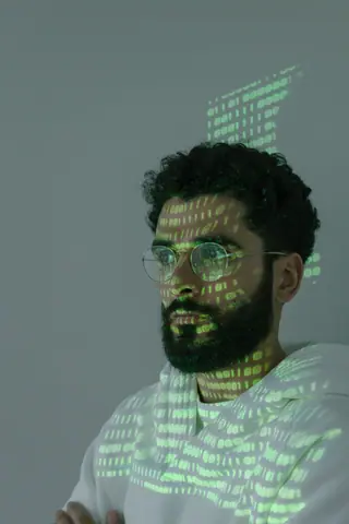 Close-up of a man with digital code projected on his face symbolizing cyber security and technology