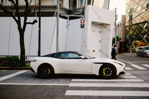 Sleek white sports car stopped at a Tokyo city intersection near designer buildings.