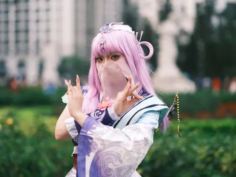 Cosplay enthusiast poses in colorful attire with lavender hair outdoors in Vietnam.